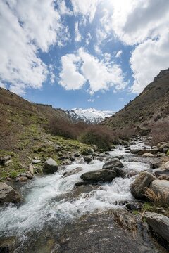 Mountain stream Rio Valdeinfierno, hiking trail near Junta de los Rios, behind Sierra Nevada with summits Mulhac&eacute;n and La Alcazaba, snow-covered mountains near Granada, Andalusia, Spain