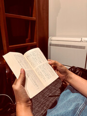 Naklejka premium Person relaxing indoors, reading a book with Japanese text