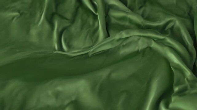 Close-up of crumpled green satin fabric with smooth texture and shiny appearance against white background.