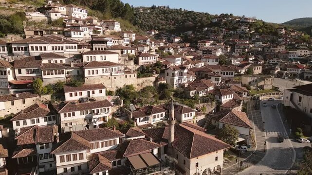 Aerial close up circular view Berat - A city of a thousand windows. Gorica Bridge crossing Osum river with Mangalem quarter Ottoman houses hillside UNESCO town Balkan travel destination in Albania