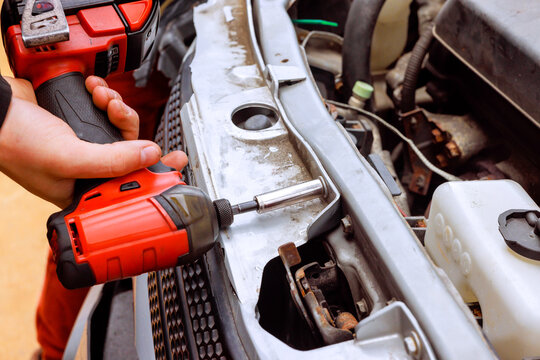 Service auto mechanic is fixing car broken with screwdriver tool in garage setting