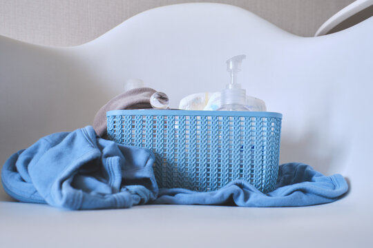 Baby essentials in a blue basket with clothing for hygiene and wellness