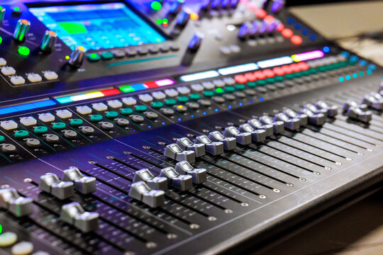 Sound worker is adjusting mixing console while working on music project in recording studio