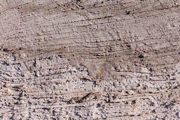 Rough concrete wall featuring a detailed textured surface, showing variations in tone and distinct horizontal and diagonal lines © EdNurg