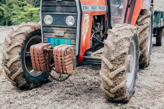12 October 2025, Valjevo, Serbia: Old red Massey Ferguson tractor with muddy tires and front counterweights, parked on a gravel road, showing agricultural work