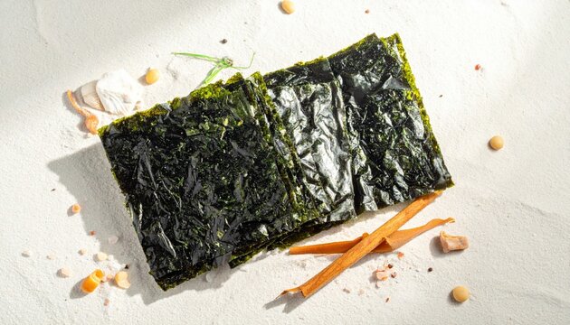 Crispy sheets of roasted nori and dulse seaweed arranged elegantly on a textured surface, showcasing a healthy and natural snack for culinary enthusiasts.
