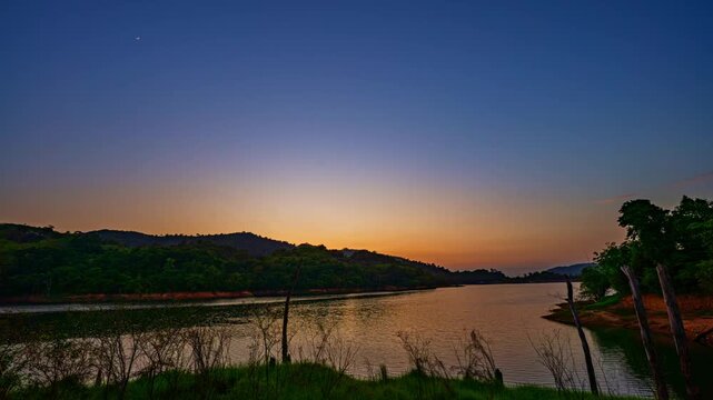Serene time lapse scene capturing vibrant sunset colors over still water, showcasing reflections and changing light at Phuket&rsquo;s largest reservoir. Ideal for concepts of calm, nature, sustainability