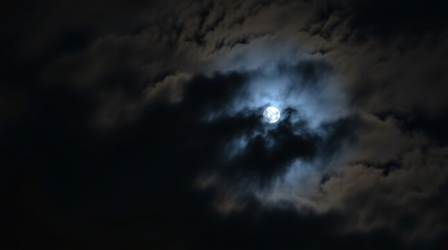 full moon shining through dark clouds at night