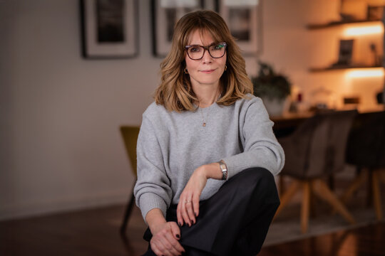 Blond haired attractive woman relaxing in an armchair in her modern apartment
