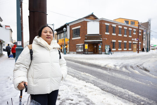 Portrait Beautiful asian fat woman smile happy travel and Standing on Sidewalk with Mountain and Cityscape Background. Enjoying a Sunny Winter Day in a Picturesque Town. posture suggests curiosity