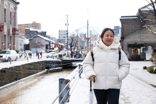 Portrait Beautiful asian fat woman tourist Visiting in Otaru, sightseeing Otaru canal with Snow in winter season. popular landmark for attractions in Hokkaido, Japan. Travel and Vacation