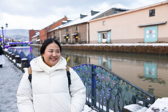 Portrait Beautiful asian fat woman tourist Visiting in Otaru, sightseeing Otaru canal with Snow in winter season. popular landmark for attractions in Hokkaido, Japan. Travel and Vacation