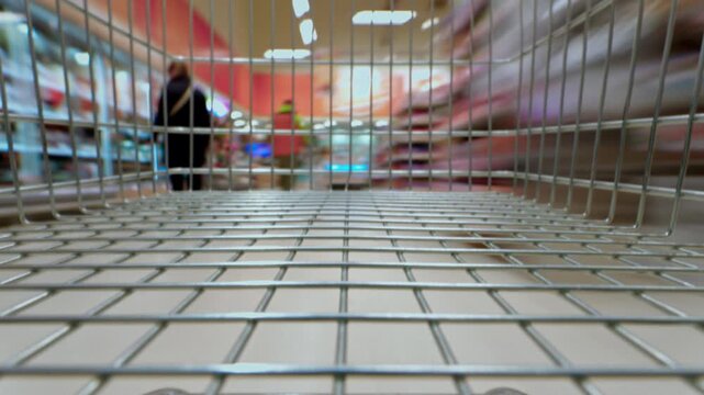 Walk through supermarket with an empty shopping cart. Customer makes purchases, spends money. Black Friday or discount season. Timelapse. Grocery store and sections with goods.
