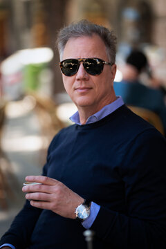 Confident mature man sitting at table at sidewalk cafe