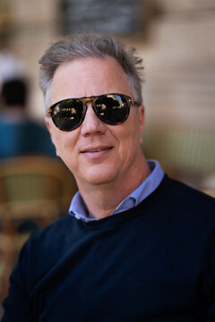 Confident mature man sitting at table at sidewalk cafe