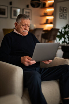Senior man wearing casual clothes and using a laptop at home