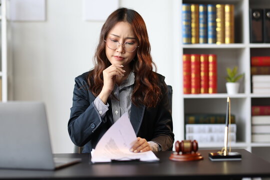 Lawyer reading legal documents and thinking about a case in her office.
