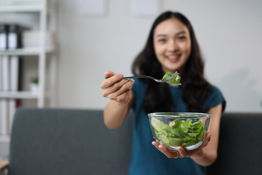 Young woman eating fresh salad at home, healthy food concept.