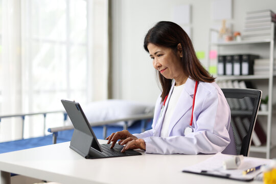 Senior female doctor working with tablet in hospital room.