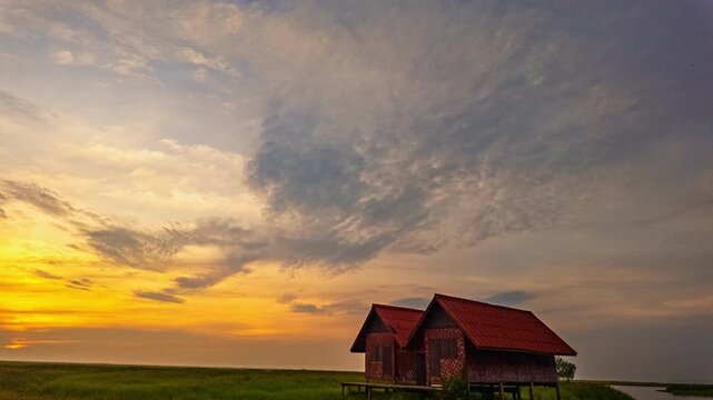 A beautiful natural background showcasing serenity, soft clouds, and warm golden tones of a Pattalung sunset, creating a calm and peaceful atmosphere across the open countryside landscape.