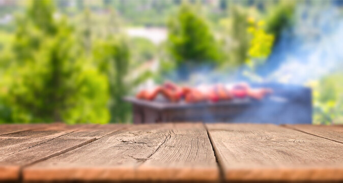 Empty wooden table with blurred barbecue grill background and smoke outdoor summer food banner