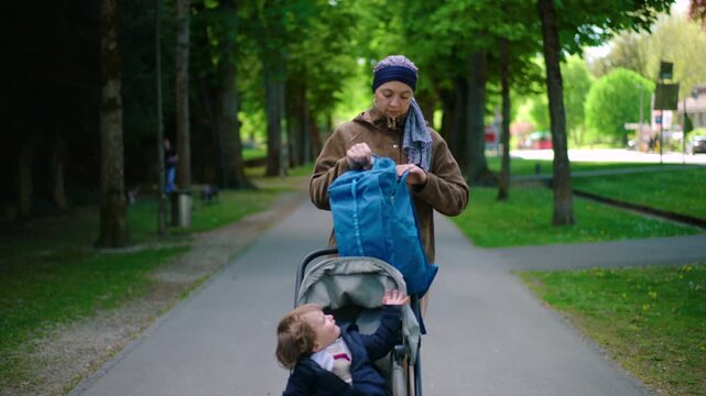 mother with cancer stopping stroller on street to take item from backpack during chemotherapy treatment showing daily parenting routine responsibility and resilience while managing illness