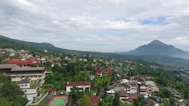 Aerial 4K view of a villa on the hillside of Puncak Tretes and the lush mountain landscape of East Java, Indonesia.