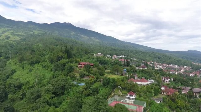 Aerial 4K view of a villa on the hillside of Puncak Tretes and the lush mountain landscape of East Java, Indonesia.
