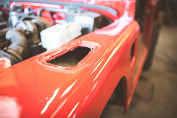 Fototapeta premium Shiny red car fender undergoing restoration in a workshop setting