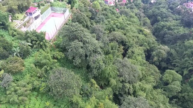 Aerial 4K view of a villa on the hillside of Puncak Tretes and the lush mountain landscape of East Java, Indonesia.