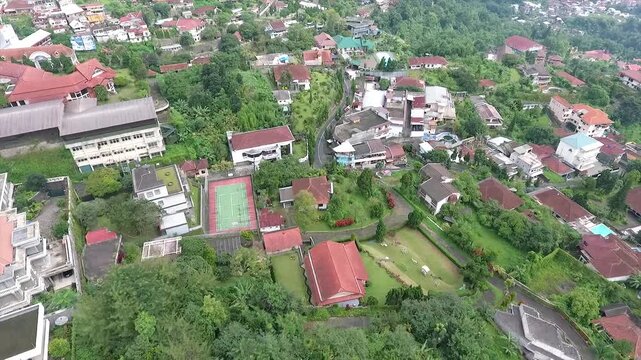 Aerial 4K view of a villa on the hillside of Puncak Tretes and the lush mountain landscape of East Java, Indonesia.