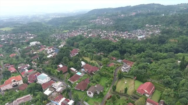 Aerial 4K view of a villa on the hillside of Puncak Tretes and the lush mountain landscape of East Java, Indonesia.
