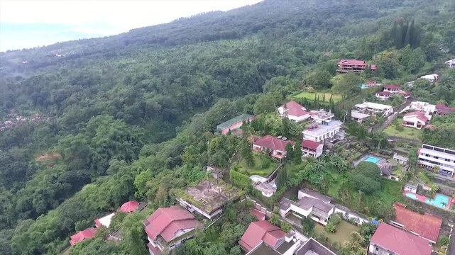Aerial 4K view of a villa on the hillside of Puncak Tretes and the lush mountain landscape of East Java, Indonesia.