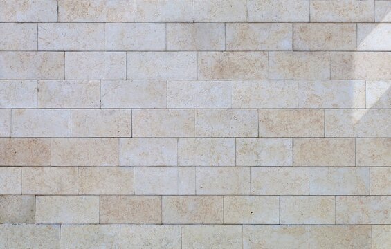 Off-white and beige travertine wall made of&nbsp; large rectangle tiles. Background and texture. Full frame.