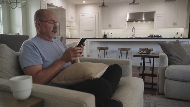 Senior Man Scrolling on smart phone while sitting at home
