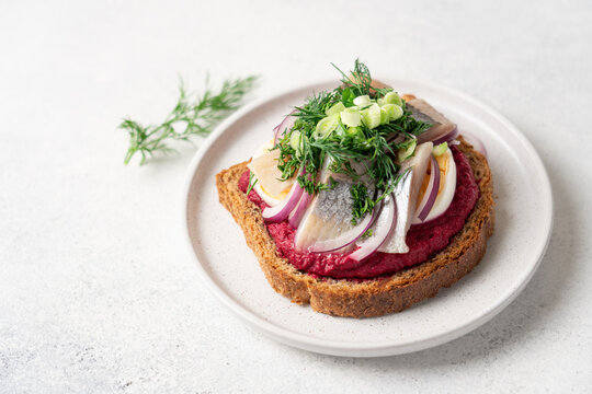 Open sandwich with herring beetroot mousse egg dill and green onion, traditional Scandinavian cuisine appetizer concept top view