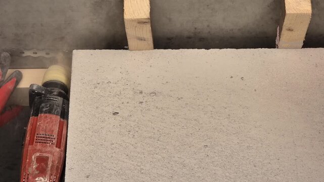Slow motion close-up of a hammer drill boring a hole into a ceiling for metal strap attachment on a building site.
