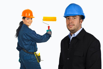Fototapeta premium Woman in blue overalls holds a yellow paint roller