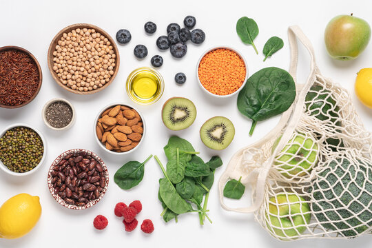 Healthy eating assortment with vegetables, fruits, berries, chickpeas, mung beans, lentils, red rice, apple, spinach, and lemon  on white background for  plant-based protein, clean eating