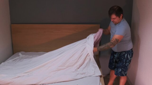 Man removing duvet from zippered duvet cover, taking out bedding for washing and cleaning, everyday household routine in bedroom interior, preparing linens for laundry and maintenance