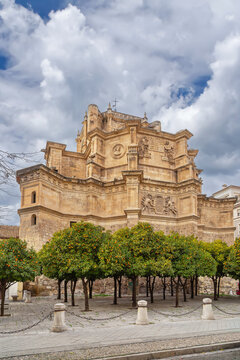 View of Monasterio de San Jeronimo in Granada Spain with orange trees. Stone monastery walls under cloudy overcast sky