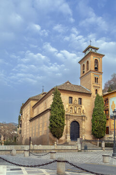 Facade of Church of San Gil and Santa Ana in Granada Spain. Mudejar architecture with brick bell tower under cloudy sky