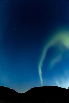 Araffes in the sky with a bright green aurora behind them, Hvitserkur, Northern Iceland, long exposure motion blur