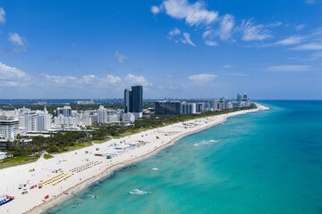 Fototapeta premium Drone aerial view of Miami sandy beach. Wide drone shot of Miami Beach and ocean waves. Miami beachscape captured from above. Oceanfront Miami resorts by drone.