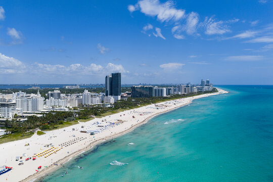 Drone aerial view of Miami sandy beach. Wide drone shot of Miami Beach and ocean waves. Miami beachscape captured from above. Oceanfront Miami resorts by drone.