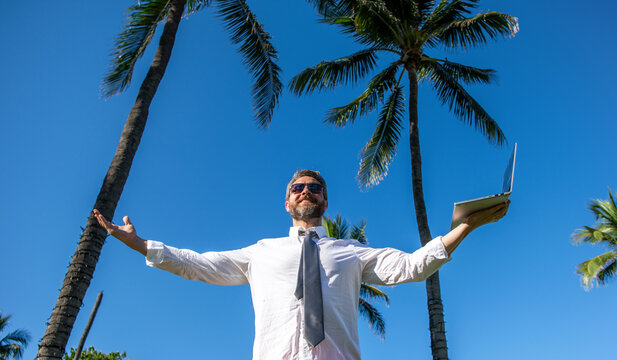 Online freelance work. Successful businessman worker with laptop. Business man using laptop among palm tree. Business trip success. Man freelance worker online. Businessman on summertime