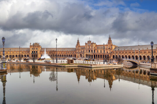 View of Plaza de Espana in Seville Spain with towers and canal. Renaissance Revival architecture under cloudy overcast sky