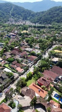 Vista a&eacute;rea de regi&atilde;o residencial pr&oacute;xima &agrave; Praia da Barra do Sahy com casas, vegeta&ccedil;&atilde;o e montanhas, destacando natureza e urbaniza&ccedil;&atilde;o no litoral paulista