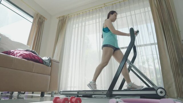 A person engaging in a home workout on a treadmill, showcasing a healthy lifestyle. The bright room is well-lit with natural light, emphasizing the importance of fitness in daily living.