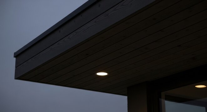 Subtle diffused illumination from a recessed soffit light casting a warm glow in the dark exterior of a modern building
